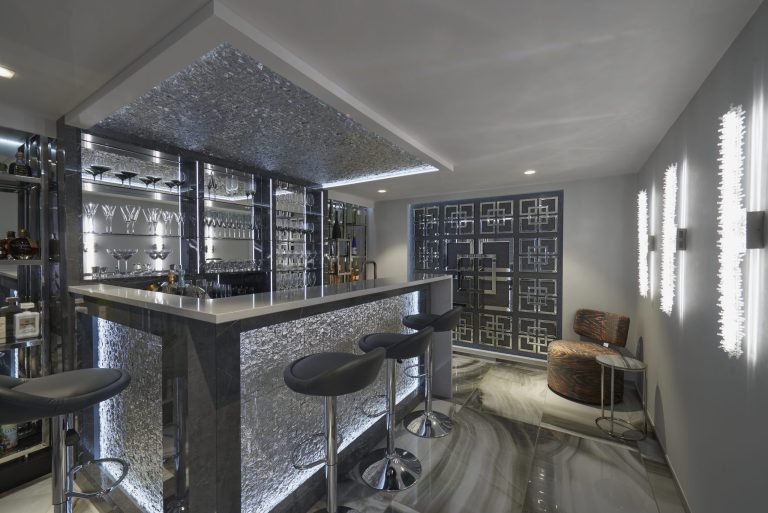 Basement bar in daylight with a mirrored back wall and glass shelving