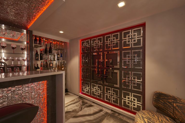 Home bar with a backlit fretwork screen and a textured glass counter