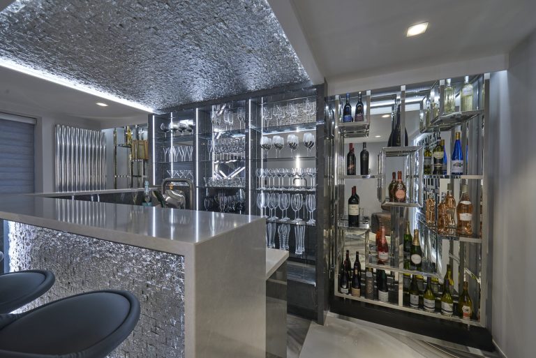 Bar shelving holding wine and glassware lit from behind