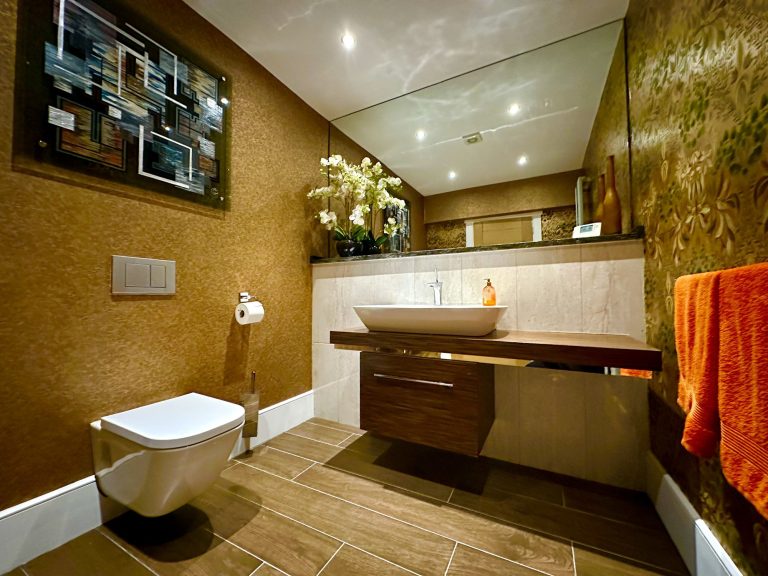 Cloakroom with a gold wall covering, timber vanity and vessel basin