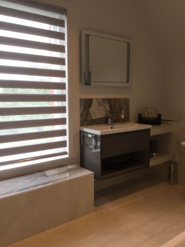 Freestanding bath with a lit niche in a marble bathroom