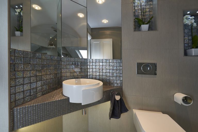 Basin set on a mosaic shelf with mirrored panels behind