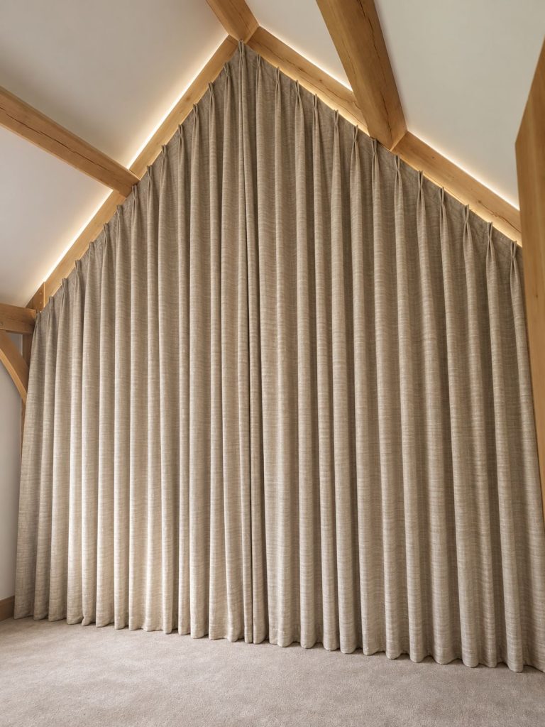 Full-height curtains in a room with an apex ceiling and exposed beams