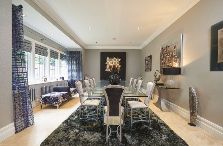 Dining room with a long table, upholstered chairs and a textured rug