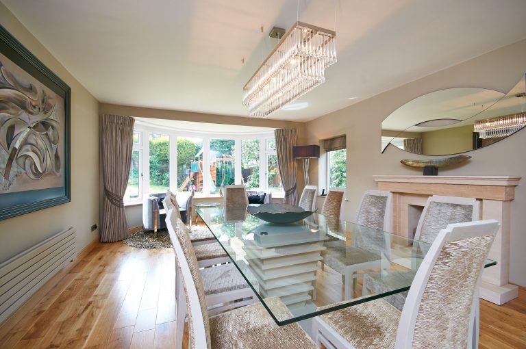 Dining room with a linear pendant above a glass table and a bay window