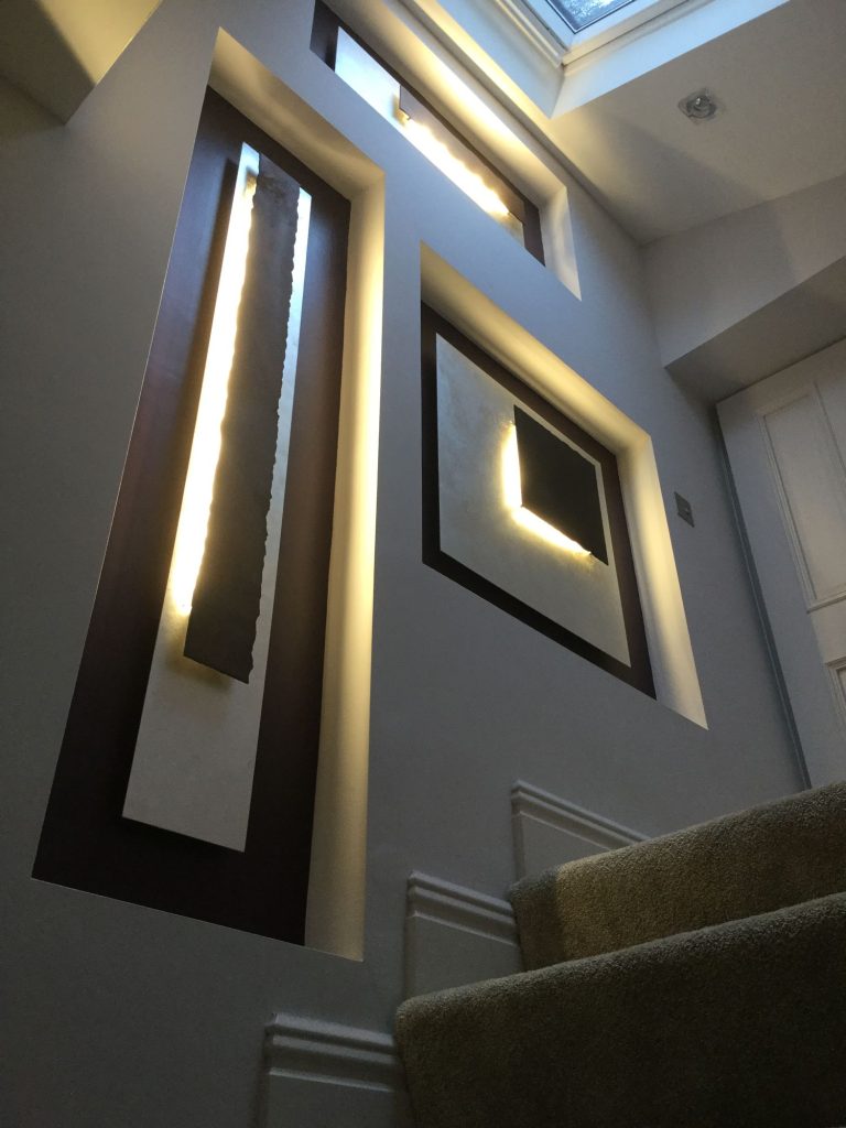 Stairwell with lit recessed wall panels running up the wall