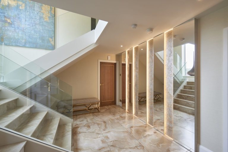 Entrance hall with a marble floor, glass balustrade and artwork along the wall