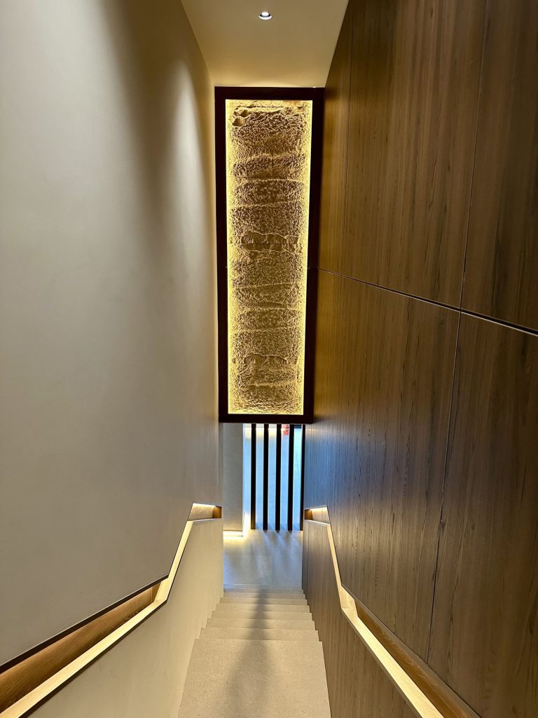 Lit wall panel above a staircase in a panelled stairwell