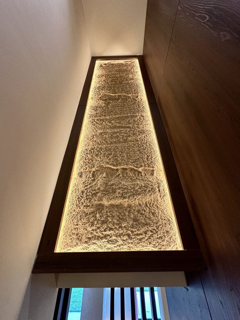 Backlit textured glass panel set into a timber wall