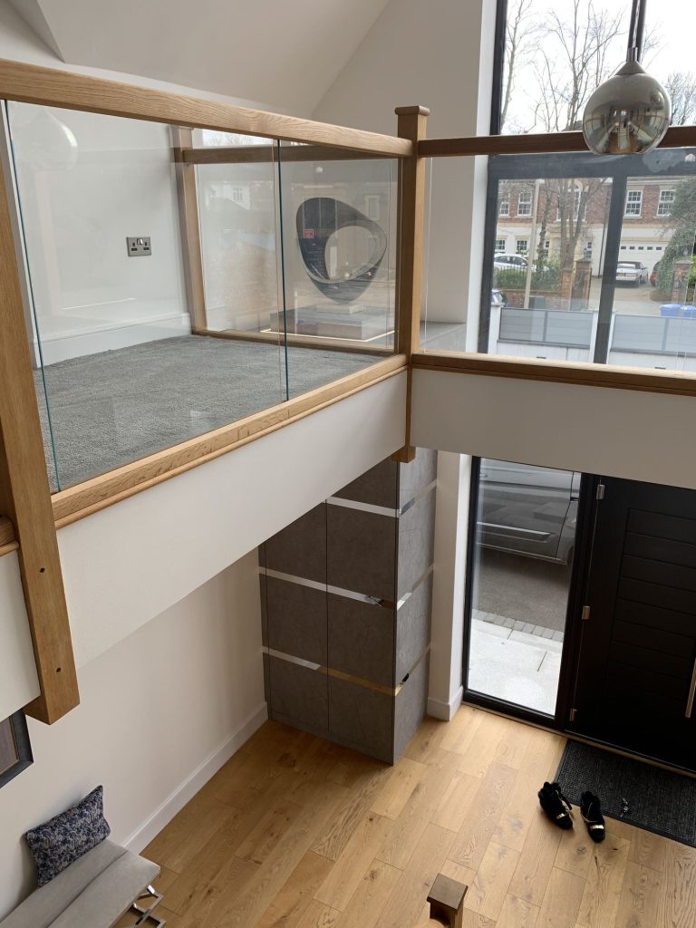 Double-height hall with a glass balustrade and full-height glazing