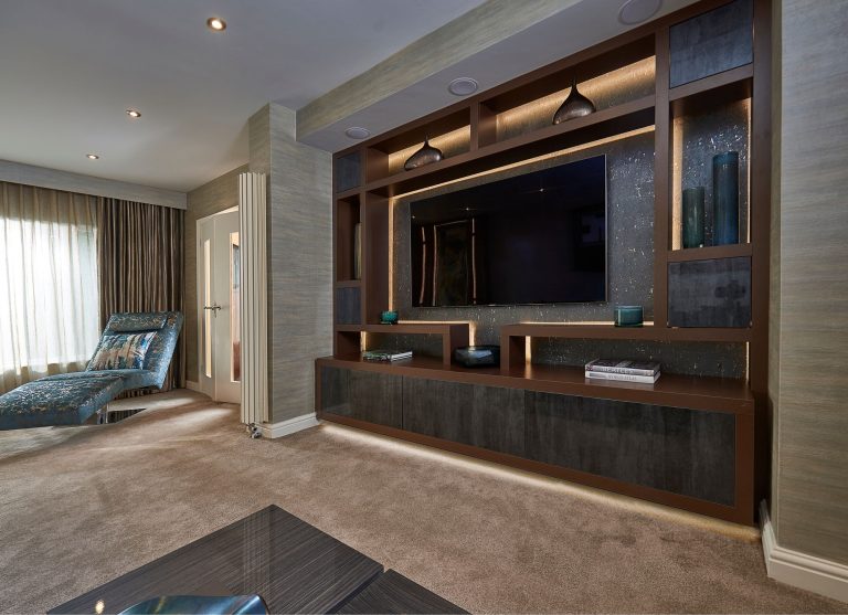Fitted media wall in brown joinery with a wall-hung television and lit display niches