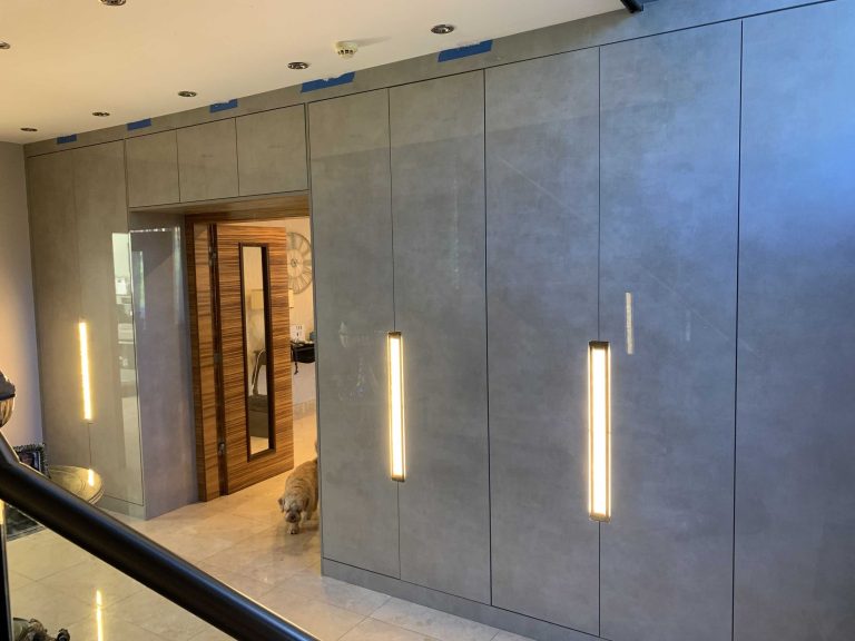 Fitted wardrobes with lit vertical handles running the length of a bedroom wall