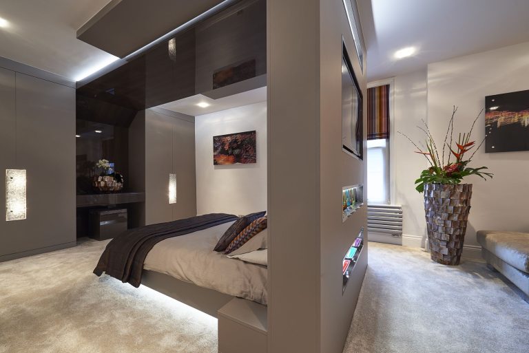 Bedroom with the bed built into a fitted canopy, mirrored wardrobes and lit glass display niches