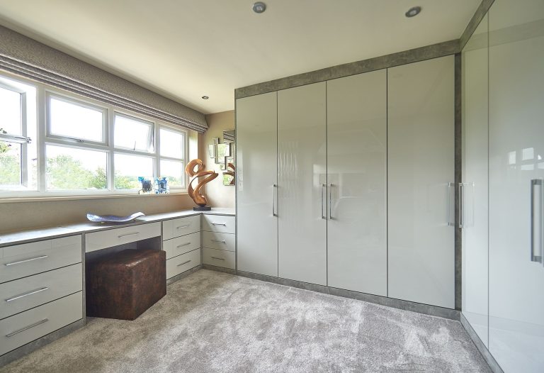 Fitted wardrobes built into the full wall of a light bedroom