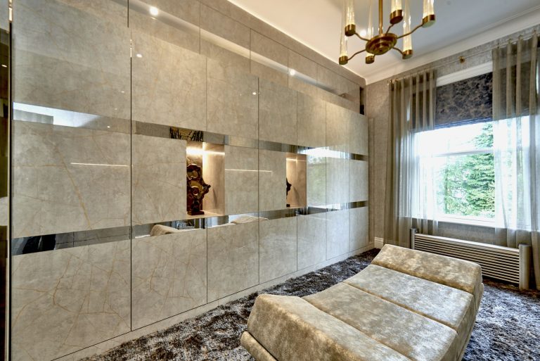 Mirrored fitted wardrobe doors reflecting a bedroom