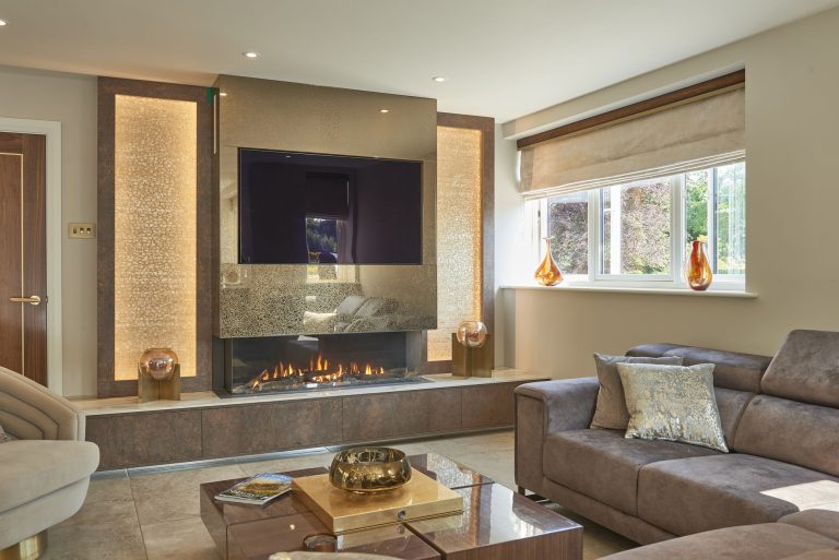 Media wall with gold leaf panels either side of a full-width fire