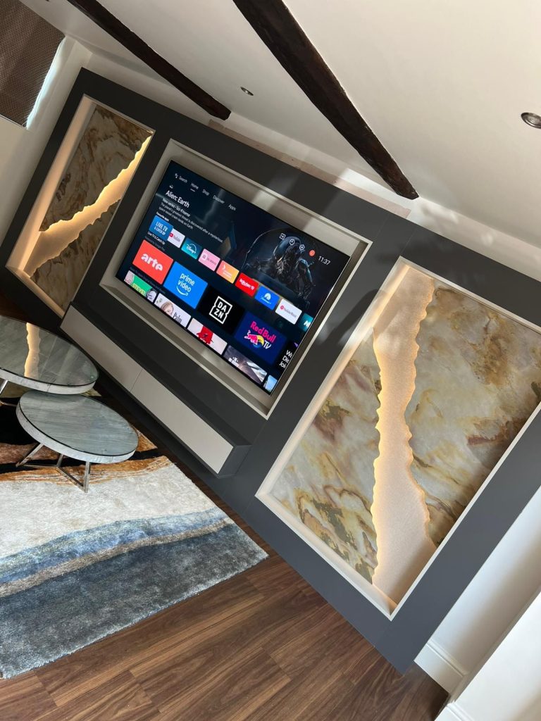 Backlit onyx panel beside the television in a media wall