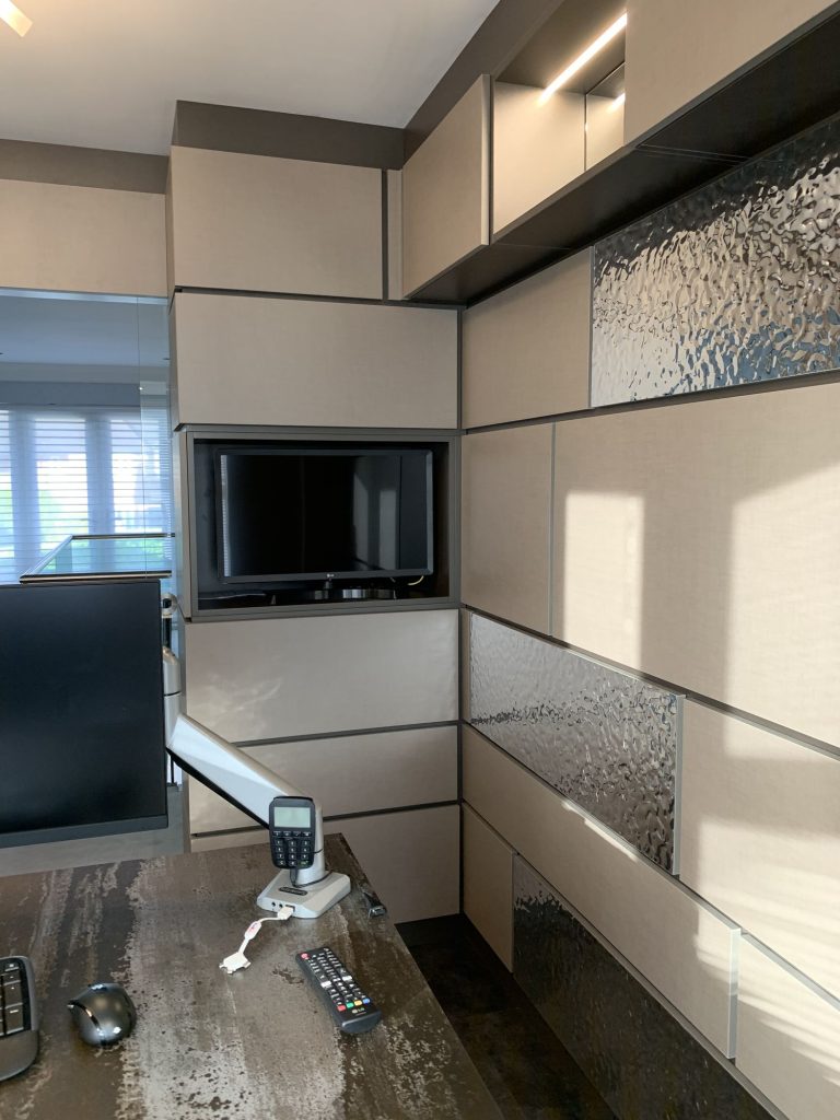 Fitted study desk with a wall-mounted screen and storage above