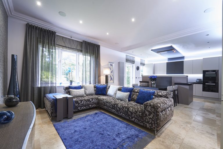 Open-plan living area with a patterned corner sofa and the kitchen beyond