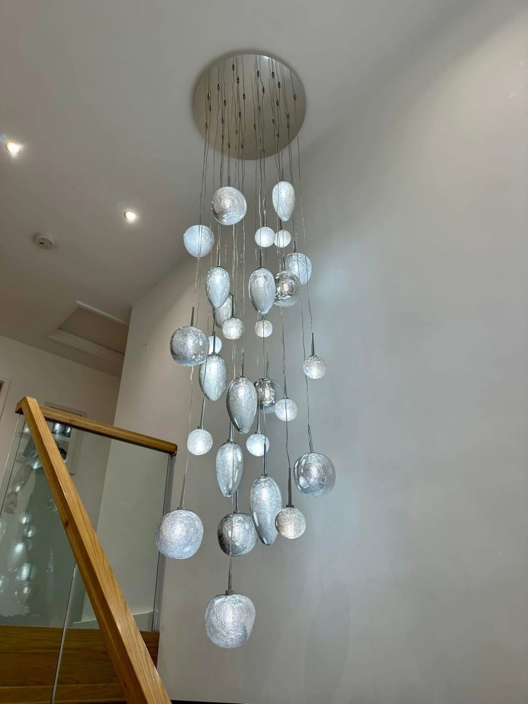 Cluster pendant of glass orbs hanging over a staircase