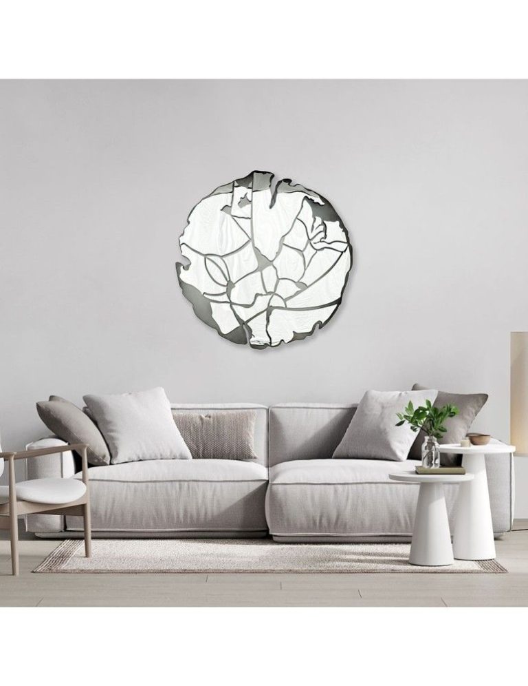 Round sculptural wall mirror above a sofa in a living room