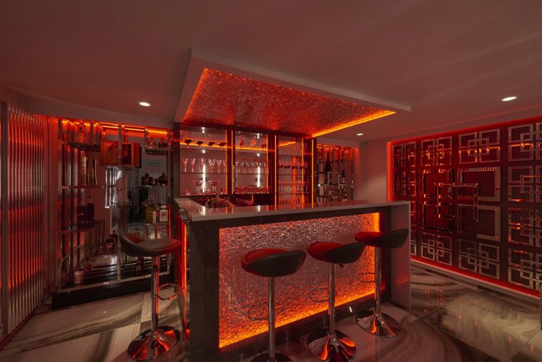 Basement bar lit red, with a fretwork screen wall and bar stools