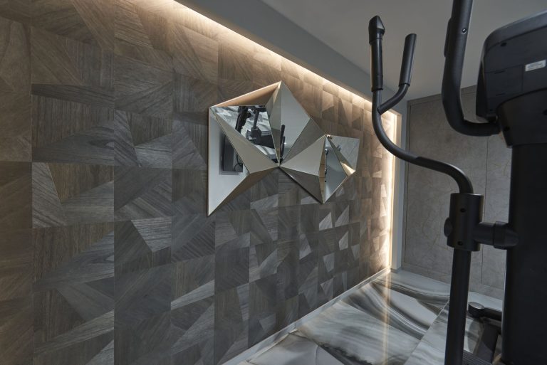 Faceted wall panelling lit from behind beside the gym equipment
