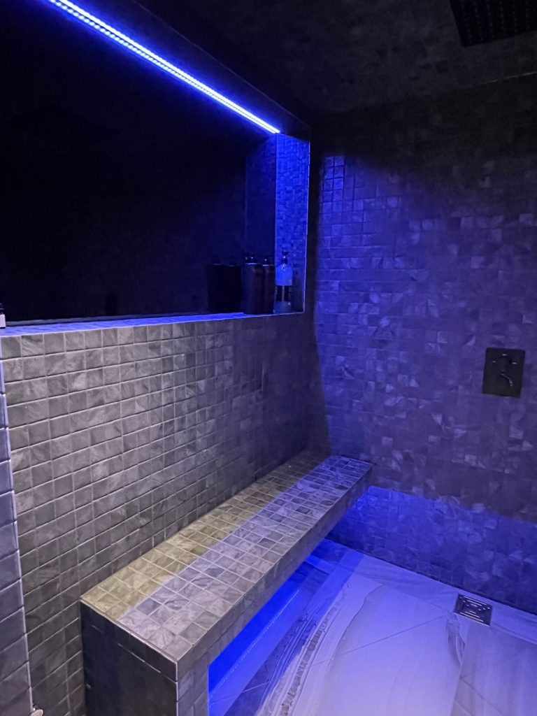Steam room bench lit blue along the wall