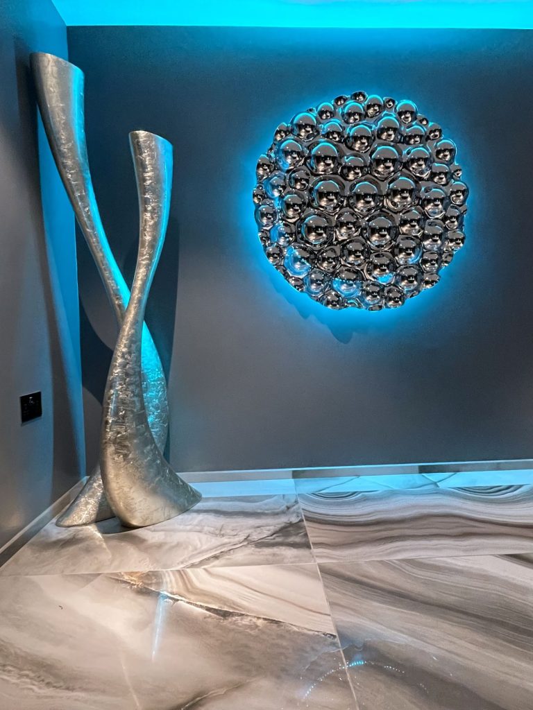 Glass sculpture and backlit wall disc beside the spa