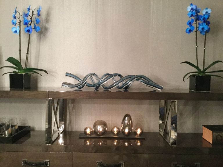 Console with a silver wave sculpture and orchids either side