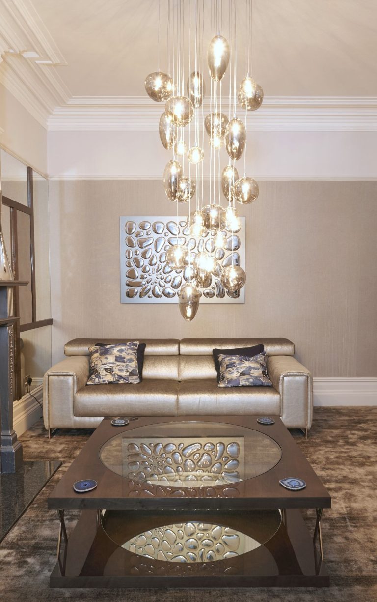 Sofa below a sculptural wall panel with the pendants beyond