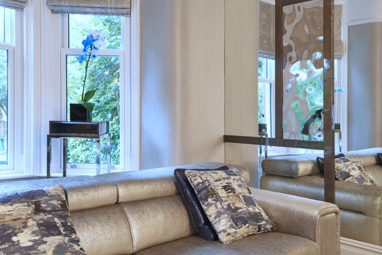 The bay window end of the lounge with the sofa and full length curtains