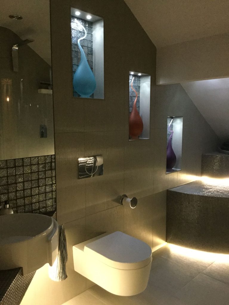 Lit niches holding glass sculptures above the basin
