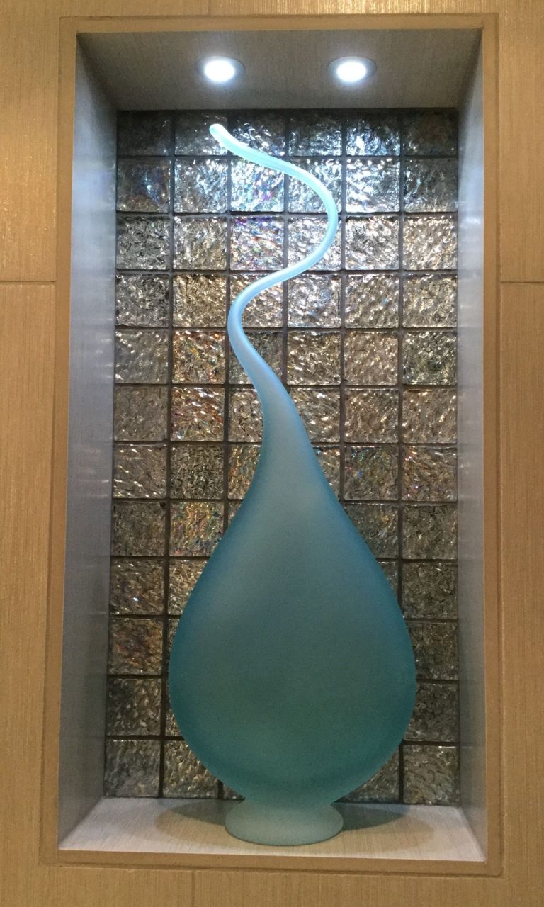 Glass sculpture lit in a niche of glass mosaic