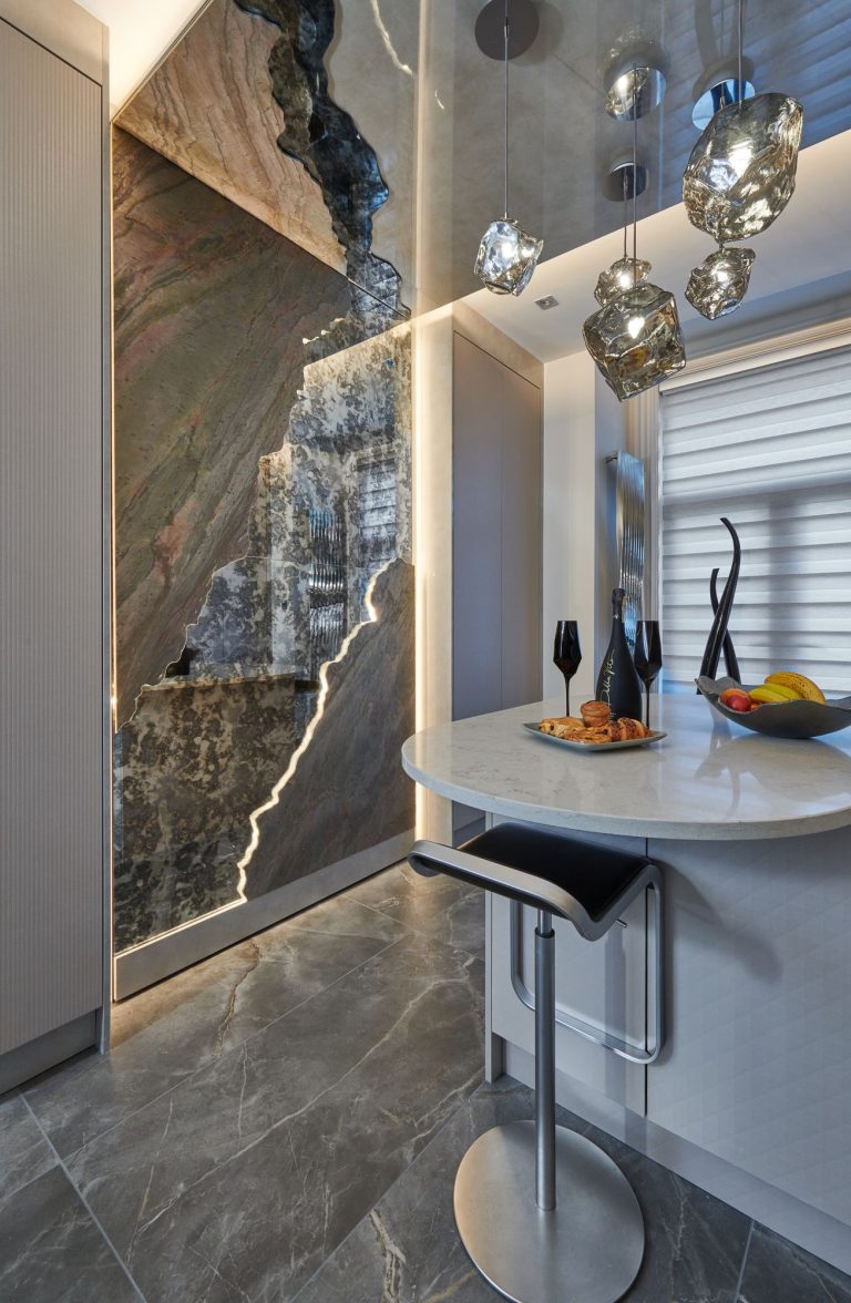 Breakfast bar below a backlit stone panel with glass pendants