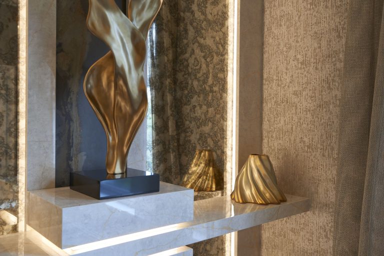 Gold sculpture on the console below a lit panel