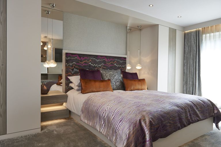 The bed with its patterned headboard panel and the mirrored wall beside it