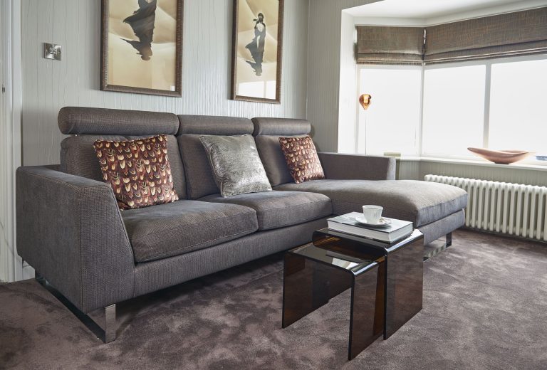 Small television lounge with a grey sofa below three framed prints