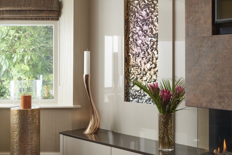 Console below a textured stone panel with a tall vase and a candle