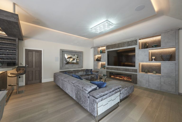 Media wall with a linear fire and lit display niches above a velvet sofa