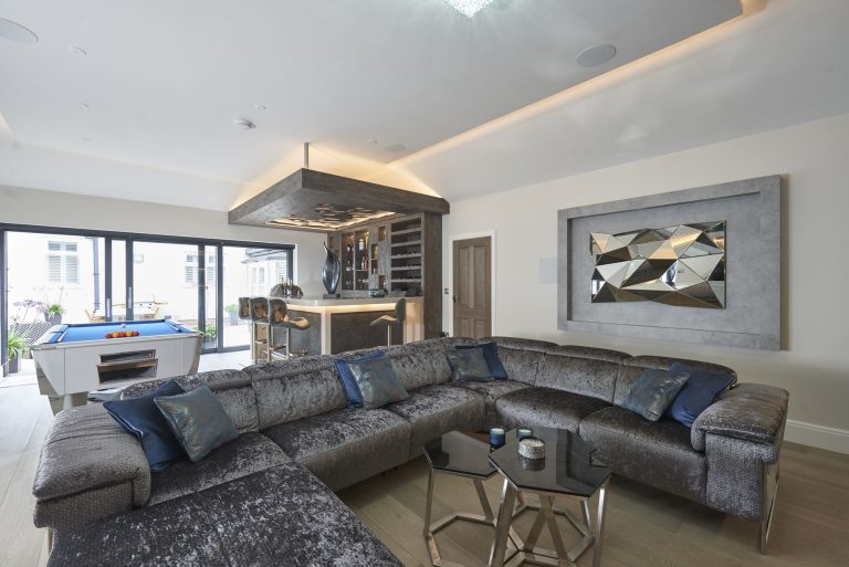 Modular sofa in grey velvet with teal cushions facing the media wall