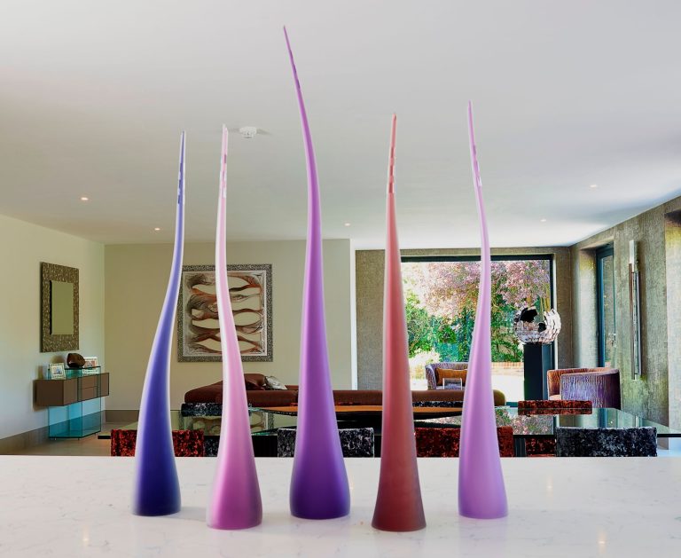 Tall coloured glass vessels used as a sculptural group