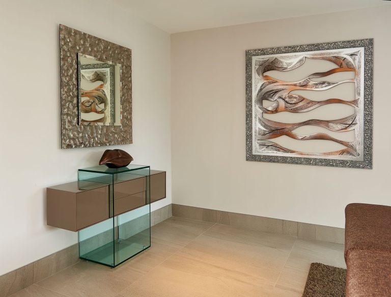 Glass console table below framed abstract artwork