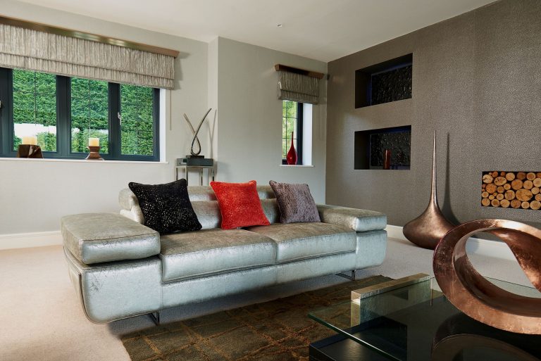 Curtains and blind at a window beside a silver leather sofa