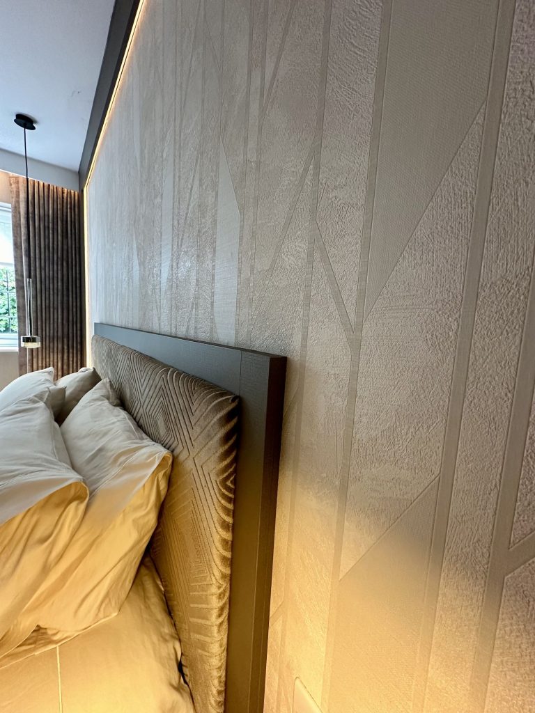 Geometric textured wallpaper behind an upholstered headboard