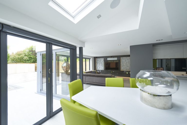 Dining area beside the kitchen with lime green chairs below a roof lantern
