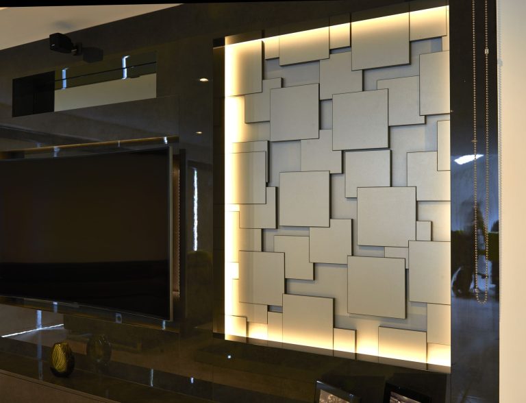 Backlit tiled panel beside the television seen from the side