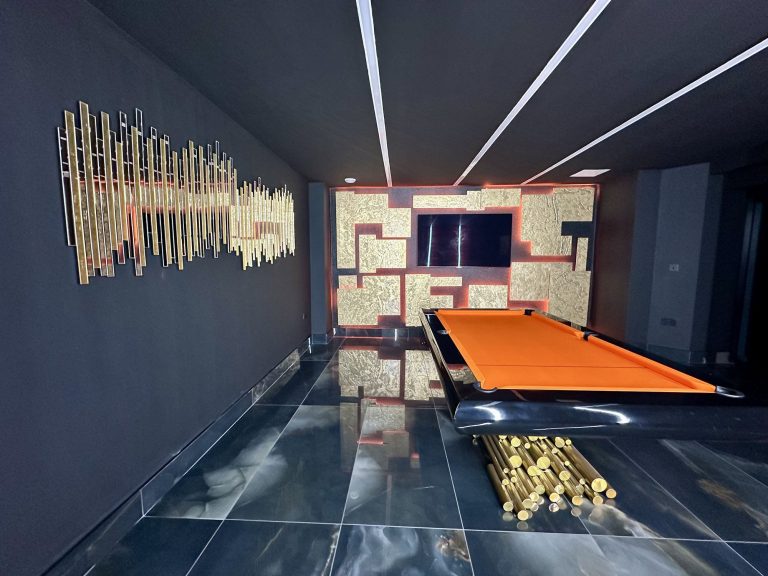 Games room with an orange pool table and a backlit gold slate feature wall