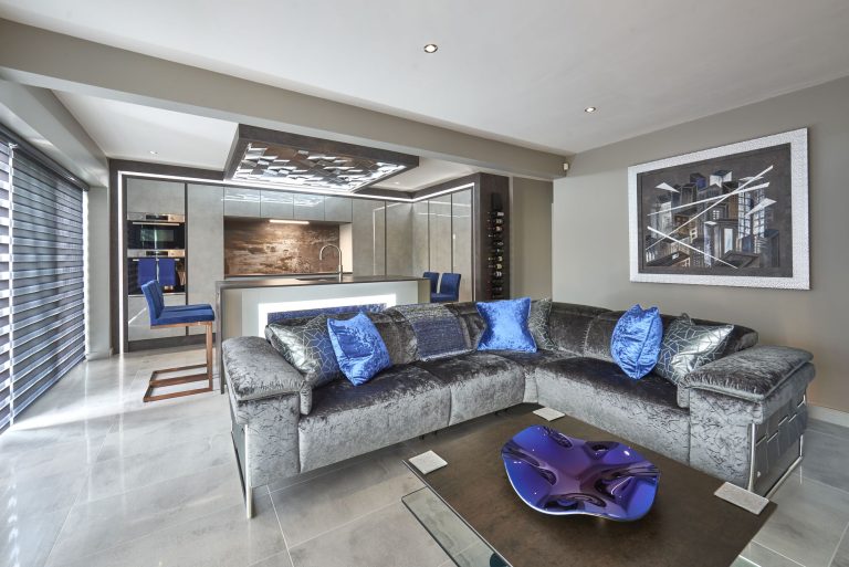 Open-plan living area with a navy velvet corner sofa and artwork