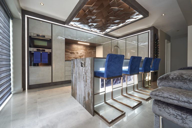 Kitchen island with navy bar stools below a sculptural ceiling panel